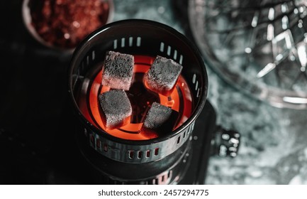 Red-hot charcoal briquettes heating in a Electric charcoal lighter for shisha, ready for smoking in a traditional Arabic hookah lounge.  - Powered by Shutterstock - Get 15% off with code: PIKWIZARD15