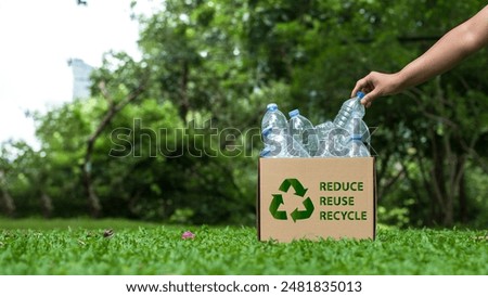 Reduce, reuse and recycle concept. A hand places a plastic water bottle into a cardboard box. An ecological metaphor for ecological waste management and a sustainable and economical lifestyle.