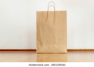 Reduce the use of plastic bags Use a paper bag instead, Disposable bag of kraft brown paper on a wooden floor, Used shopping bag on white wall cement concrete background with free copy space. 