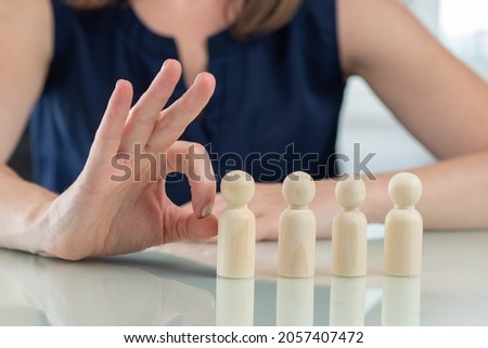 Reduction of staff. Dismissal from work. Optimization of the company staff. A businesswoman or HR manager is going to drop a wooden man. Selection of a candidate for dismissal.