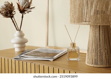 Reed diffuser with magazines on commode near beige wall, closeup