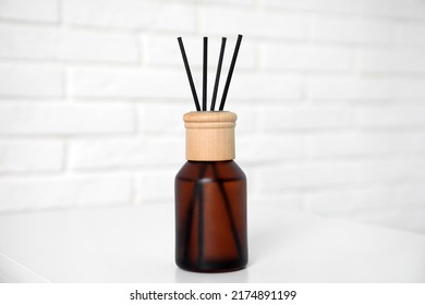 Reed diffuser on table near white brick wall, closeup