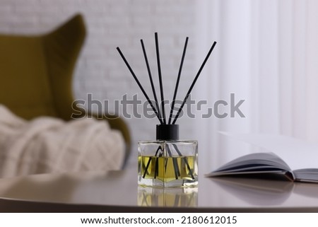 Reed diffuser on white table indoors. Cozy atmosphere