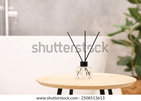 Reed diffuser on wooden table in bathroom, space for text