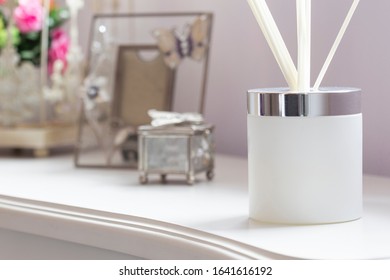 Reed Diffuser With Sticks In A Frosted Glass Jar On A White Sideboard With Ornaments