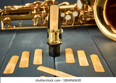 Reed mounted on saxophone mouthpiece, set of replacement reeds and the instrument at the bottom