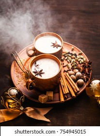reeky Masala tea chai latte traditional hot Indian teatime ceremony sweet milk with spices, herbs organic infusion healthy beverage in porcelain cup on wooden table background. Christmas style 