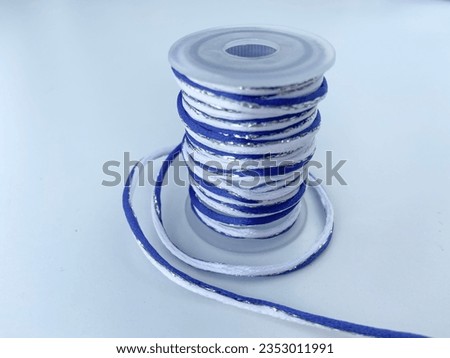 Reel of blue and white thread on white background.