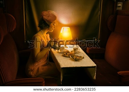 Reenactment scene of a 1920s flapper dress lady enjoying high tea in an authentic 1927 steam train compartment