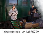 Reenactment scene on the platform near an authentic 1927 first class train wagon where a posh 1920s lady is waiting for her luggage