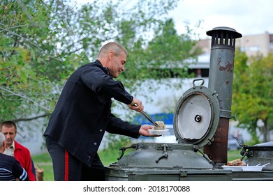 Reenactor Cook Dressed In Uniform Of USSR Navy Sailor Puts Food In The Plate From The Field Mobile Kitchen. October 4, 2012. Kiev, Ukraine