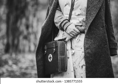 Re-enactor Wears Historical German Nurse Paramedic Of World War II Uniform With First Aid Kit. Photo In Black And White Colors. WWII WW2.