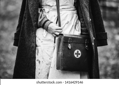Re-enactor Wears Historical German Nurse Paramedic Of World War II Uniform With First Aid Kit. Photo In Black And White Colors. WWII WW2.