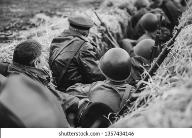 Re-enactors Dressed As World War II Russian Soviet Red Army Soldiers Hidden Sitting In Trench. Photo In Black And White Colors. WWII WW2.