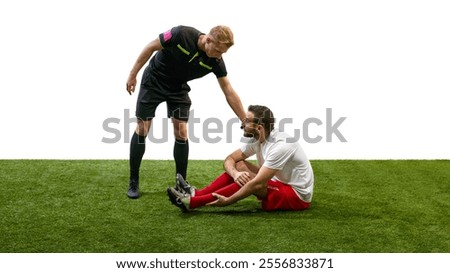 Referee calling for help, standing next to man sitting on floor with injured leg during match, isolated on white background. Concept of sport, fair play, competition, control, rules