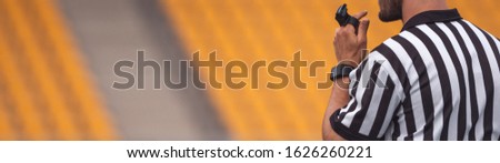 a referee with a whistle at a stadium