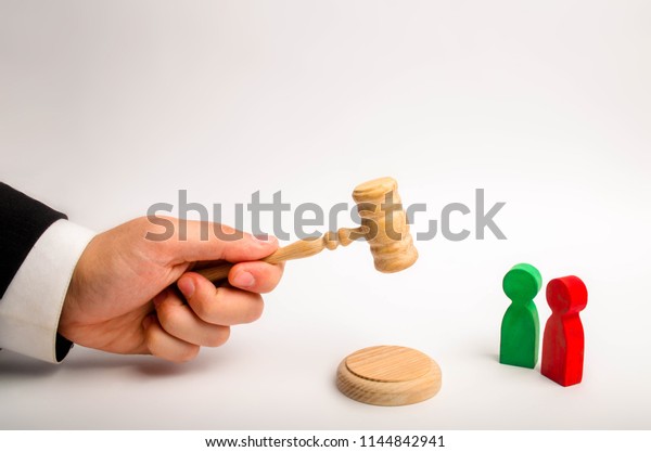 The referee\'s hand holds a hammer and issues a\
verdict in the dispute between the red and green opponents. court\
cases, the resolution of disputes and charges between the defendant\
and the plaintiff.