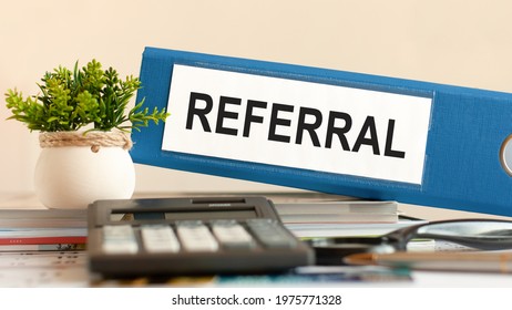 Referral - Blue Binder On Desk In The Office With Calculator, Pen And Green Potted Plant. Can Be Used For Business, Financial, Education, Audit And Tax Concept. Selective Focus.