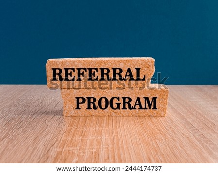 Referral program symbol. Brick blocks with text REFERRAL PROGRAM. Beautiful dark blue background, wooden table. Business concept.
