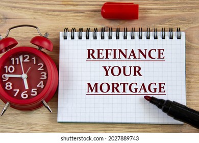 REFINANCE YOUR MORTGAGE - words in a notebook on a wooden background with an alarm clock and a marker. Business concept - Shutterstock ID 2027889743