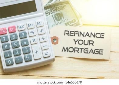REFINANCE YOUR MORTGAGE Words on tag with dollar note and calculator on wood backgroud,Finance Concept