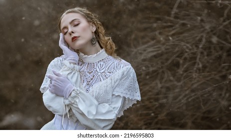 A Refined Aristocratic Lady In A White Lace Dress Walks In An Old Autumn Park. Victorian Style. Historical Reconstruction.