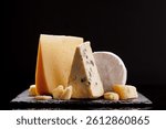A refined selection of aged cheeses presented on a board, set against a dramatic dark background. A perfect setting for a gourmet indulgence