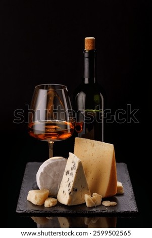 A refined selection of aged cheeses presented on a board, accompanied by a glass of wine, set against a dramatic dark background. A perfect setting for a gourmet indulgence