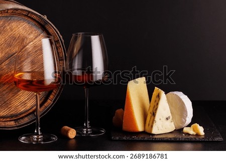 A refined selection of aged cheeses presented on a board, accompanied by a glasses of wine, set against a dramatic dark background. A perfect setting for a gourmet indulgence