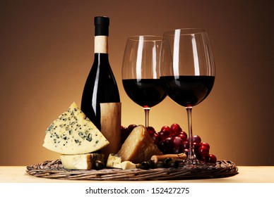 Refined still life of wine, cheese and grapes on wicker tray on wooden table on beige background - Powered by Shutterstock