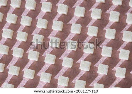 Refined sugar on pink background.Cubes of sweet and white sugar in geometricshape. Hard shadows