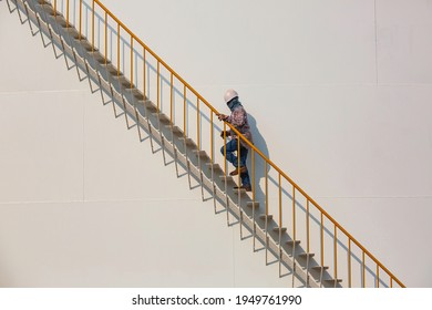 Refinery Factory Worker Climbing Up Metal Stairs Staircase Industry On Big Storage Tank Oil.