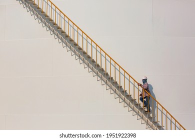 Refinery Factory Worker Climbing Up Metal Stairs Staircase Industry On Big Storage Tank Oil.