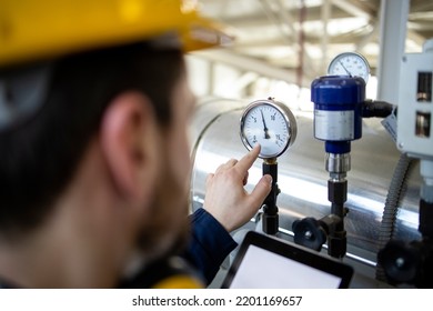 Refinery Worker Looking At Manometer And Controlling Pressure Of Natural Gas Inside Pipes.