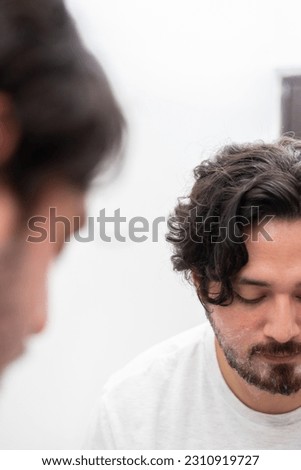 Reflecion in mirror of man looking down with shaving cream in face
