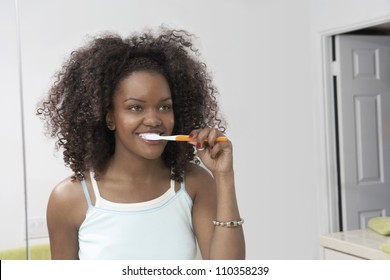 Reflection Of African American Woman In Mirror Brushing Teeth