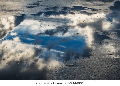 Reflection of the amazing cloudscape on the sky in the puddle.