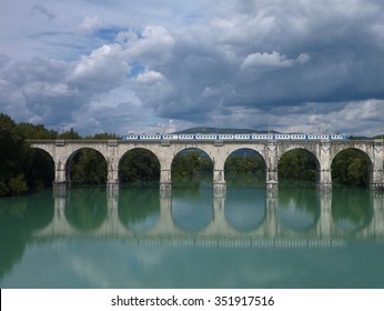 reflection of an arched bridge with train in deep blue water - Powered by Shutterstock