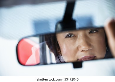 Reflection Of Asian Woman In Rearview Car Mirror.