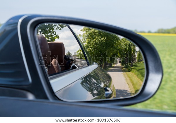 Reflection\
of asphalt highway road at the Convertible car side mirrow. Travel\
by Luxury Convertible Sports Car summer\
season