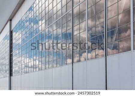 Reflection Background: Airplane Hangar with Reflective Glass under Blue Sky and Clouds