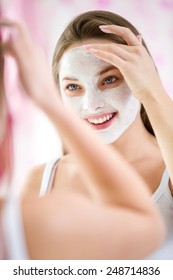 Reflection Of Beautiful Young Woman Doing Cosmetic Mask On Her Face