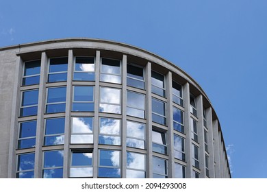 The reflection of a blue sky with clouds in the windows of a curved, reflective, office building.  Image has copy space.