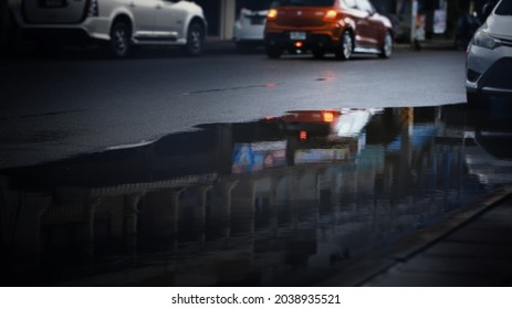 Reflection of blurry cars in puddle on the city street after hard rain fall,selective focus.Rainy season,
Transportation background. 