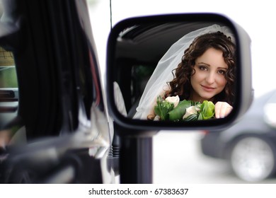 reflection of the bride's face in the rearview mirror in the car