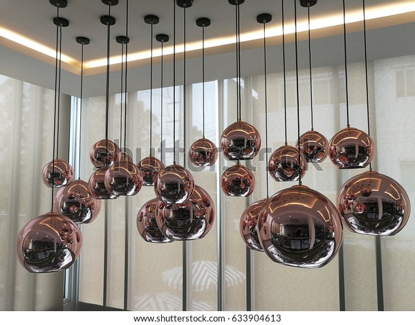 The reflection in the bulb of rose\
gold color ceiling lamp that hanging on the floor of\
roof.