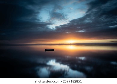 A reflection of a burning sunset and a cloudy sky on the still water of Ringkobing Fjord with a boat