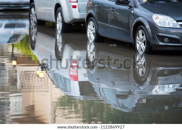 A\
reflection of a car in the water, flooding the\
street