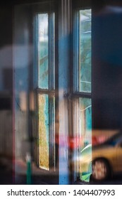 Reflection of car in window with view to window in far wall