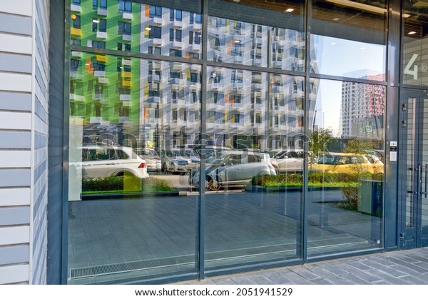 Reflection of cars and houses in the glass of the\
entrance to the\
house